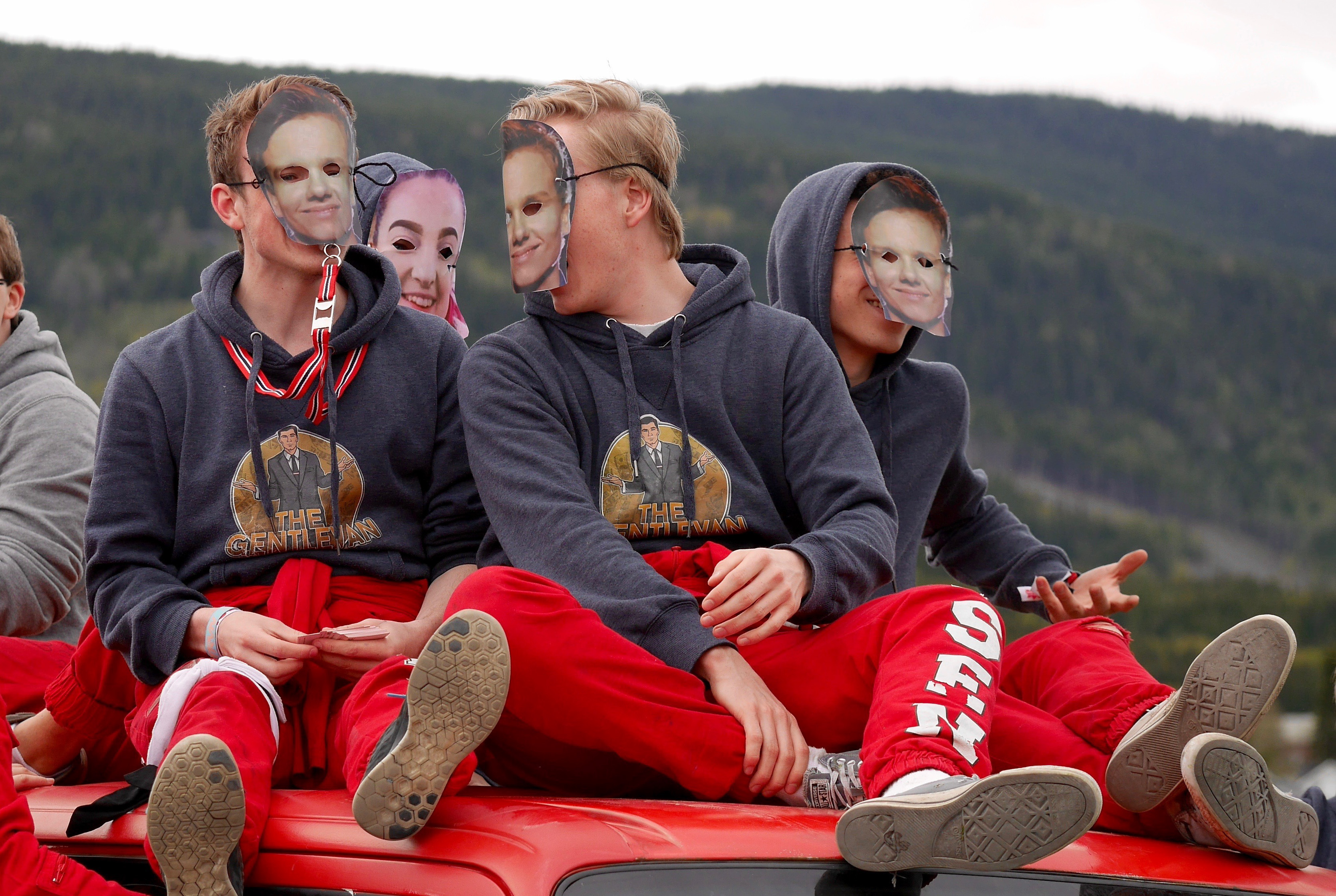 Ungdommer i russedress som sitter oppå en rød russebil.