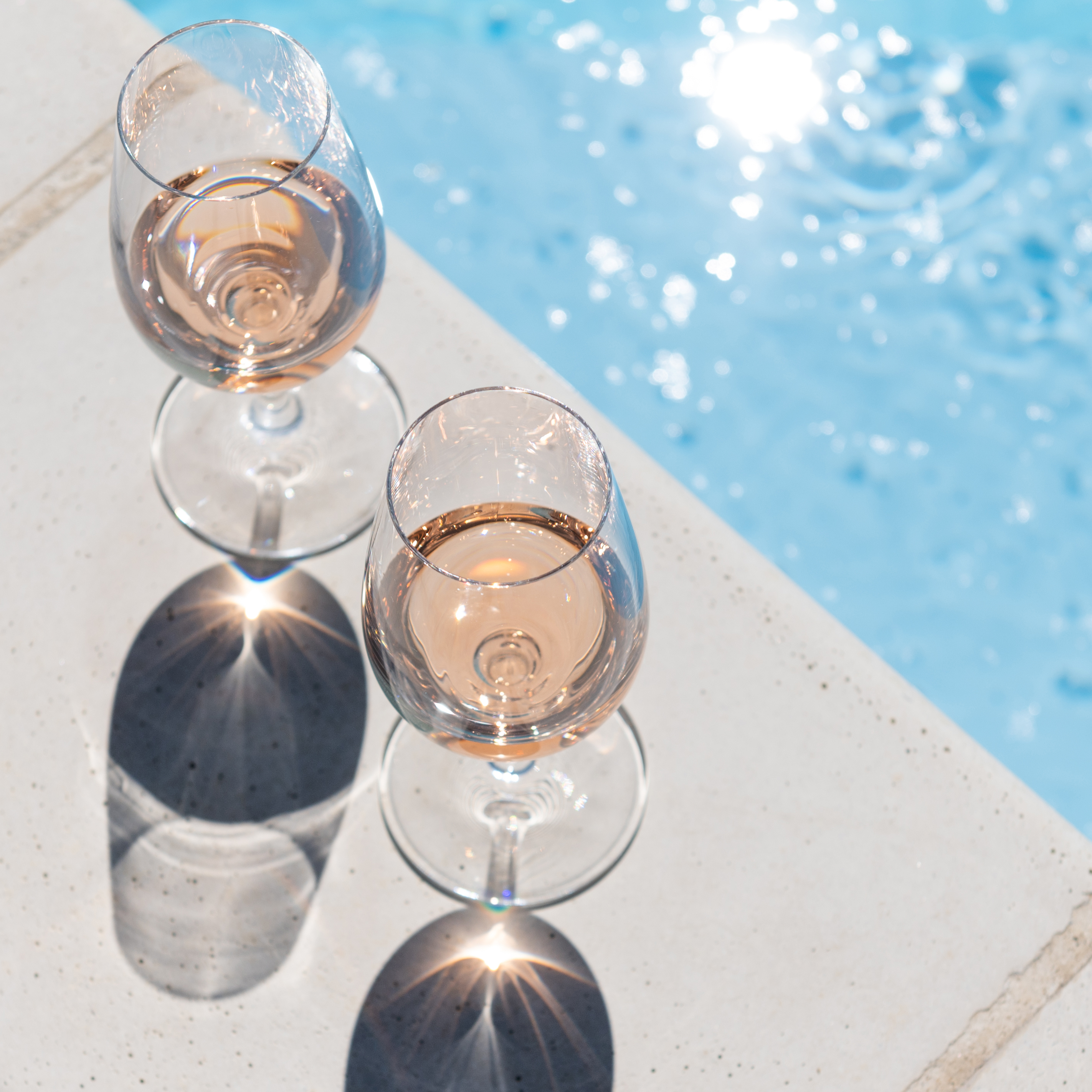 Menn og kvinner skåler med vin mens de spiser ute i solen